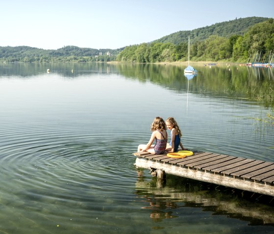 Mädchen sitzen auf dem Steg am Laacher See, © Eifel Tourismus GmbH, Dominik Ketz